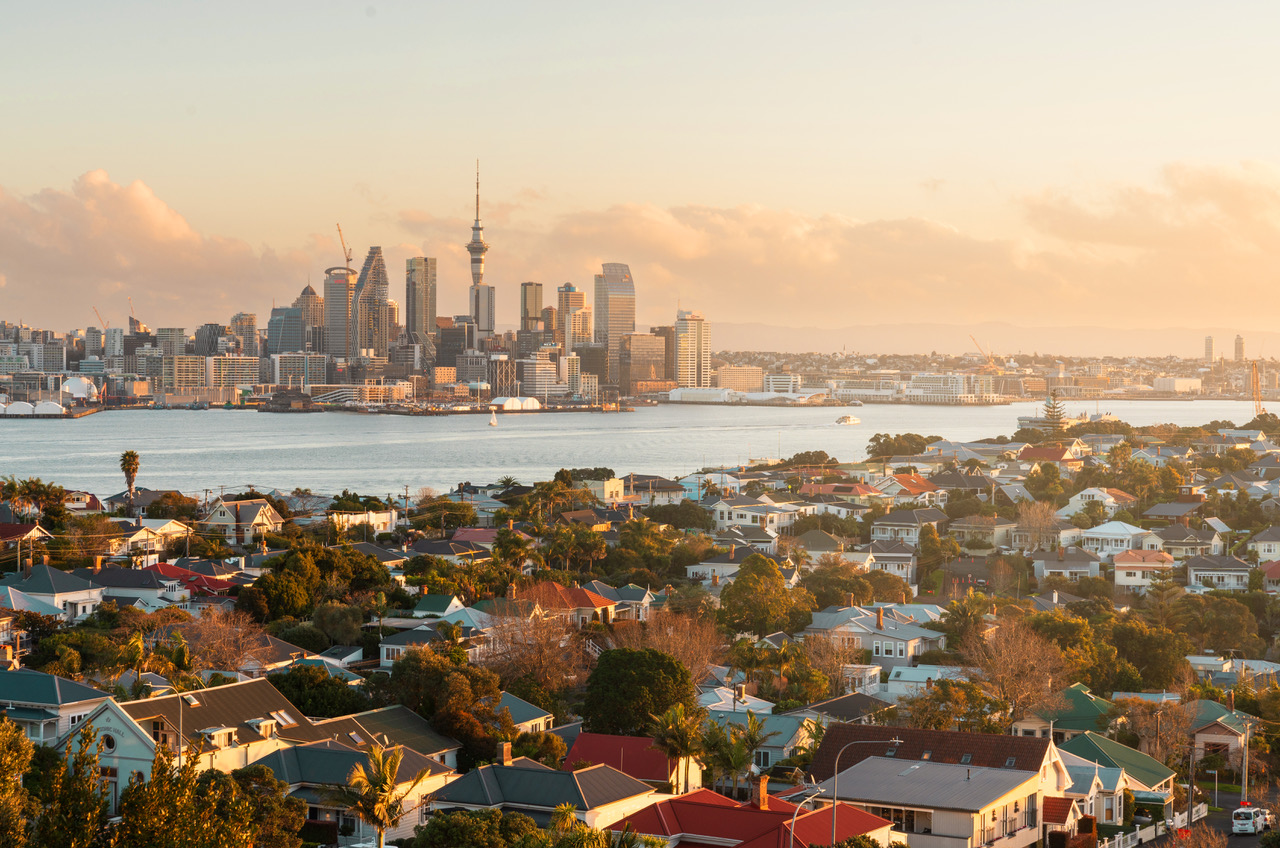 Auckland city skyline and harbour at sunset, viewed over residential homes